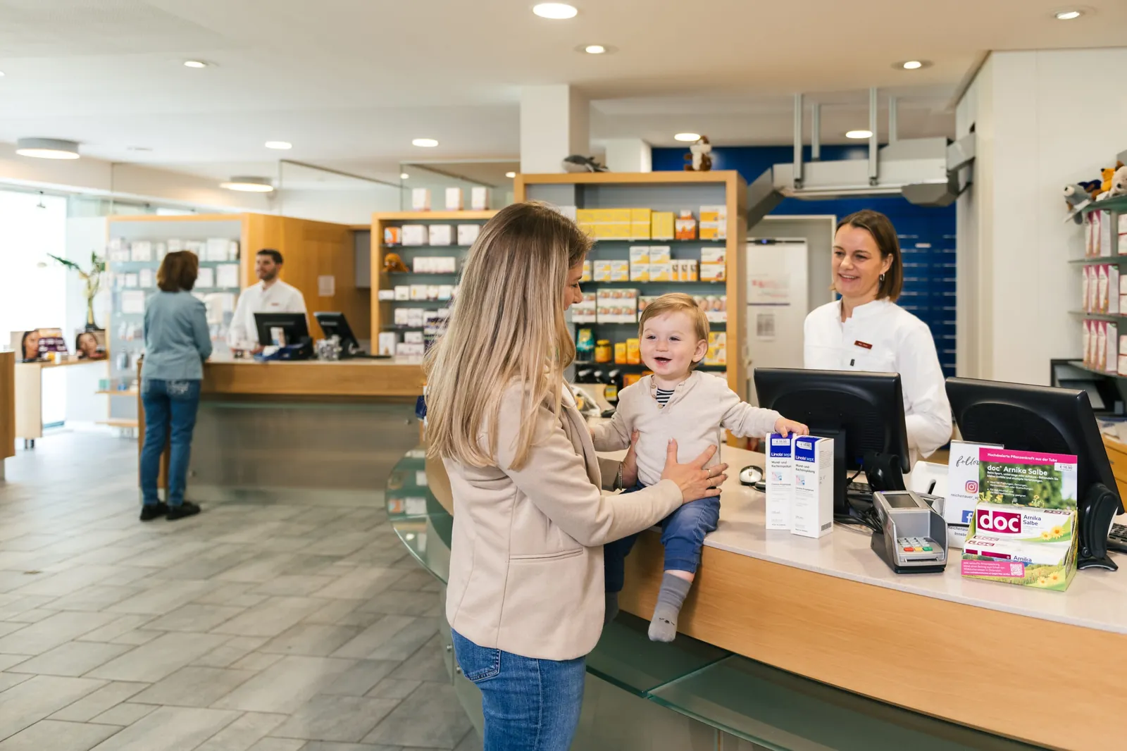 Eine Apothekerin berät eine Mutter mit Kleinkind an der Tara