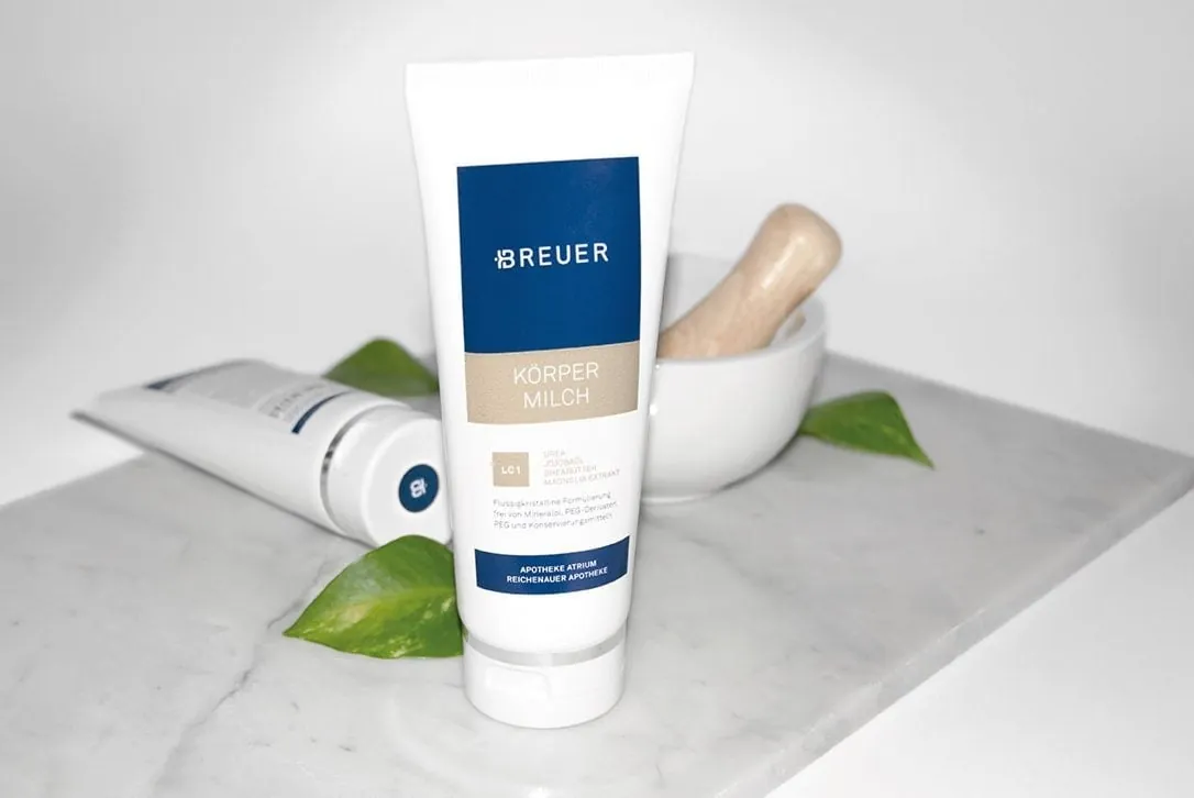 Tube Breuer Cosmetics Körpermilch auf Marmor mit Mörser und grünen Blättern