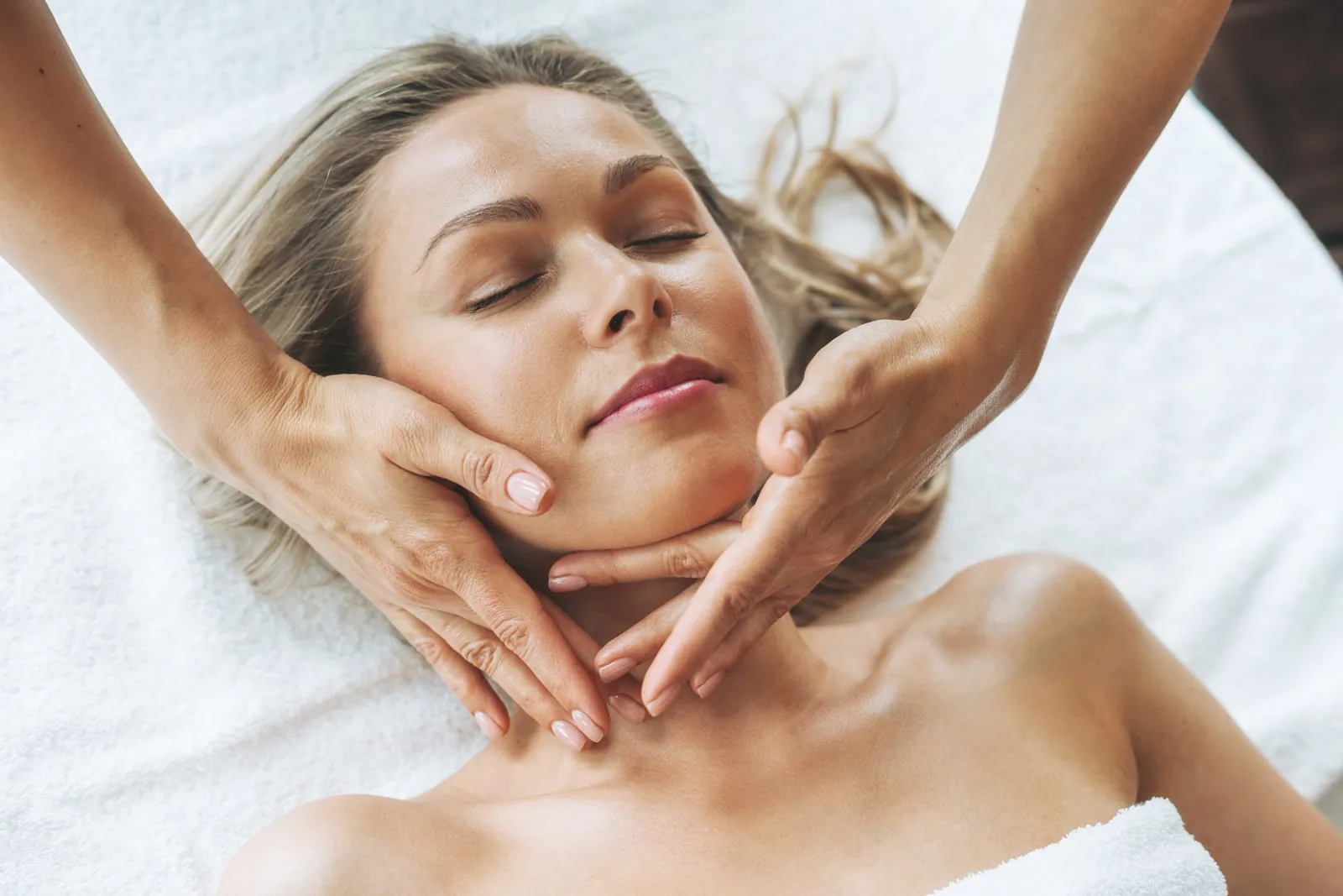 Entspannte Frau bei einer Gesichtsbehandlung mit Massage